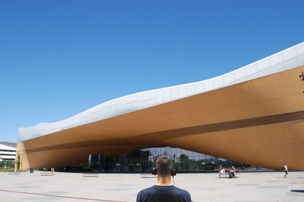 man listening to Arto´s audio tour while looking at the Oodi library
